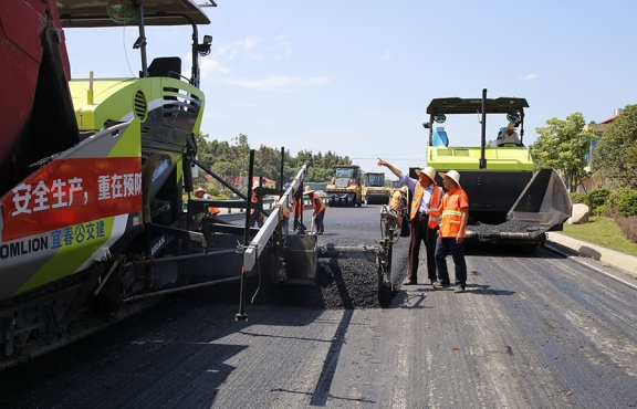 攤鋪機(jī)、壓路機(jī)等設(shè)備緊張有序運(yùn)行，高達(dá)170℃的瀝青混合料炙烤著公路人